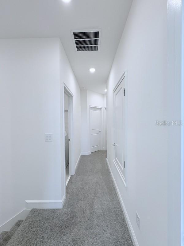 corridor featuring visible vents, baseboards, recessed lighting, and carpet floors