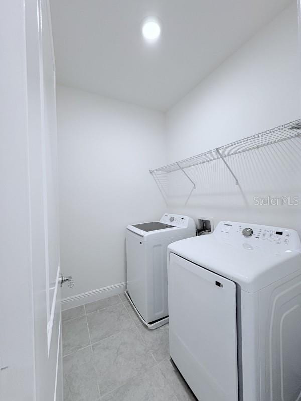 clothes washing area with washer and dryer, laundry area, and baseboards