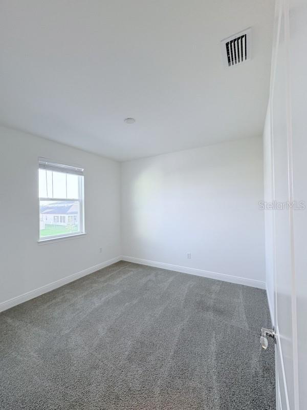 unfurnished room with visible vents, baseboards, and carpet