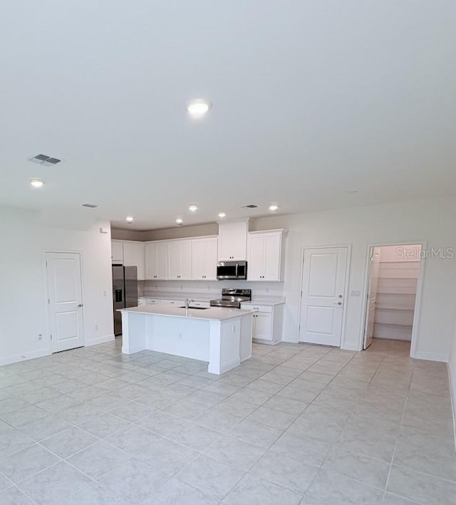 kitchen featuring white cabinets, light countertops, an island with sink, and stainless steel appliances
