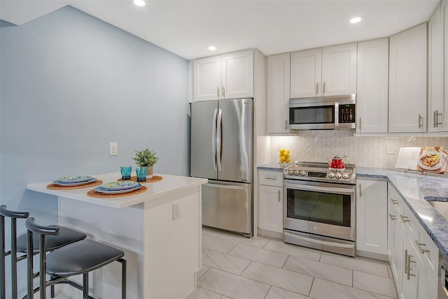 kitchen with stainless steel appliances, white cabinetry, and backsplash