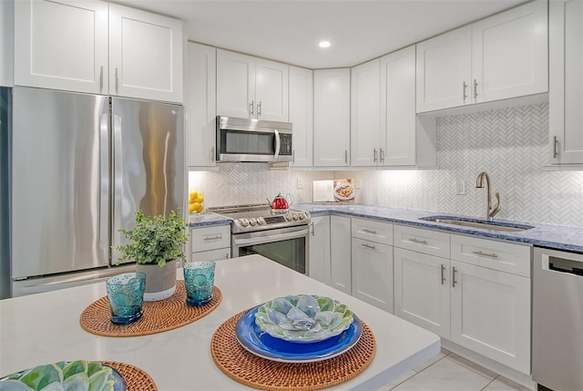 kitchen featuring sink, white cabinetry, stainless steel appliances, light stone countertops, and backsplash