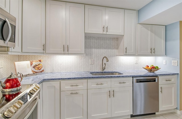 kitchen featuring sink, appliances with stainless steel finishes, backsplash, light stone countertops, and white cabinets