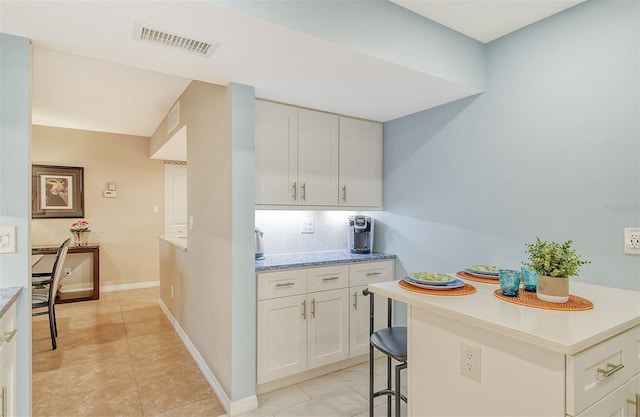 kitchen featuring white cabinetry, decorative backsplash, a breakfast bar area, and a kitchen island