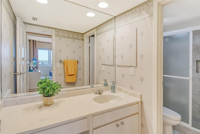 bathroom featuring vanity, toilet, and a shower with shower door