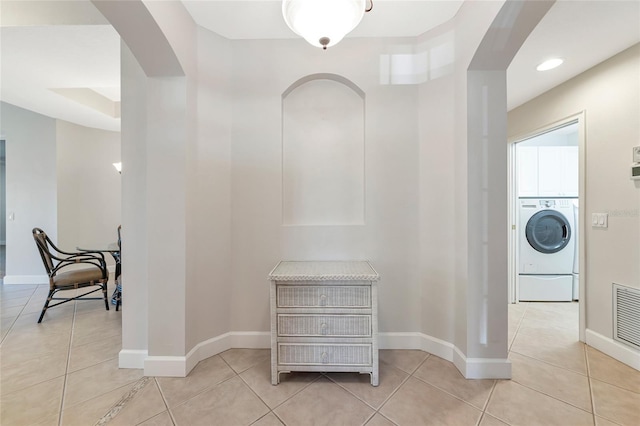 corridor with light tile patterned flooring and washer / dryer