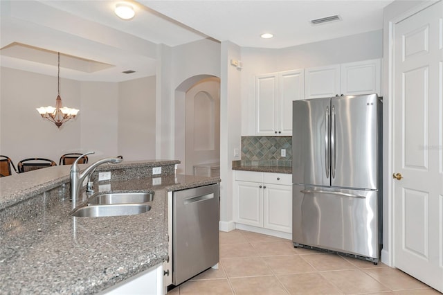 kitchen featuring pendant lighting, sink, appliances with stainless steel finishes, white cabinetry, and dark stone countertops