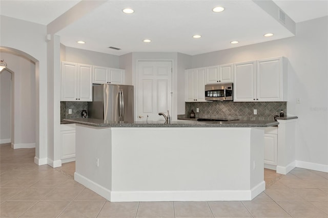 kitchen with a kitchen island with sink, light tile patterned flooring, white cabinets, and appliances with stainless steel finishes