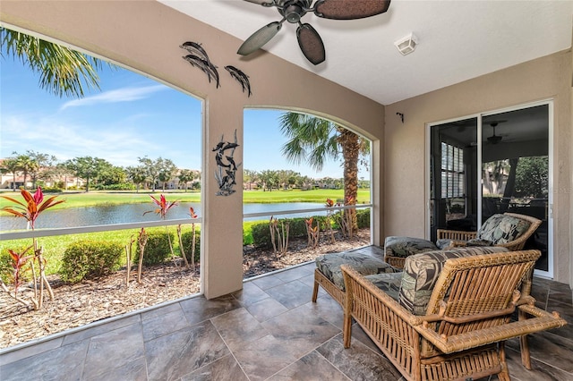 sunroom featuring a water view and ceiling fan