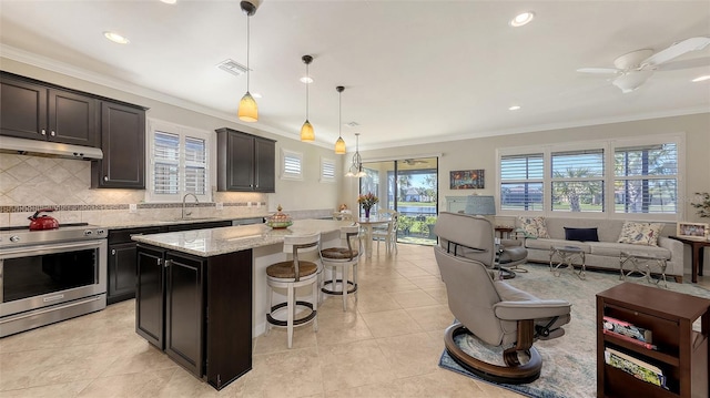 kitchen featuring stainless steel electric range, light stone countertops, pendant lighting, a center island, and sink