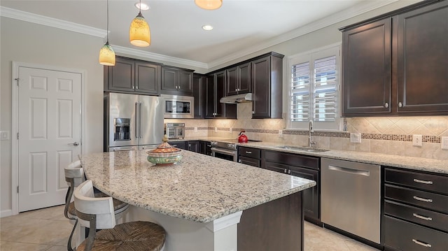 kitchen with decorative light fixtures, a kitchen island, sink, ornamental molding, and appliances with stainless steel finishes