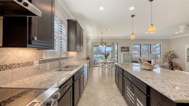 kitchen featuring ornamental molding, sink, hanging light fixtures, and light stone countertops