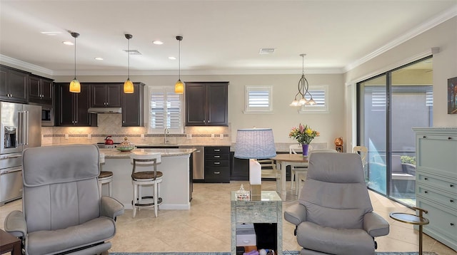 kitchen with high end fridge, light stone counters, decorative backsplash, pendant lighting, and a kitchen island