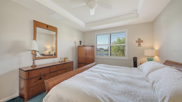 bedroom with ceiling fan, a tray ceiling, and ornamental molding