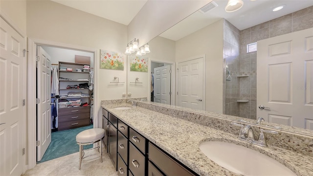 bathroom featuring tile patterned flooring, vanity, and tiled shower