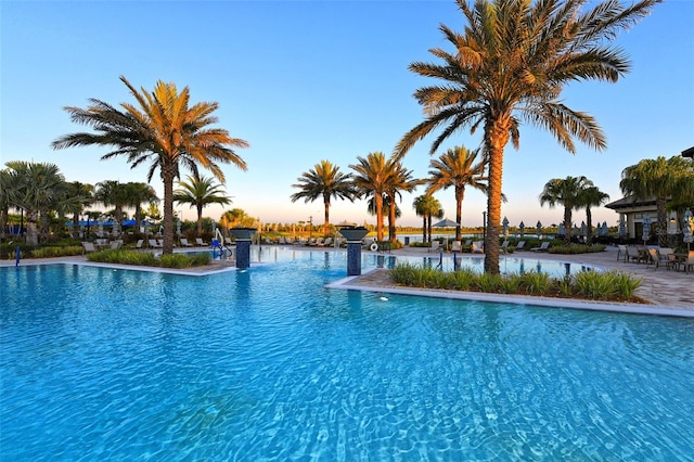 pool at dusk featuring a water view