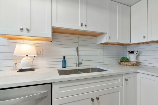 kitchen with white cabinetry, backsplash, stainless steel dishwasher, and sink
