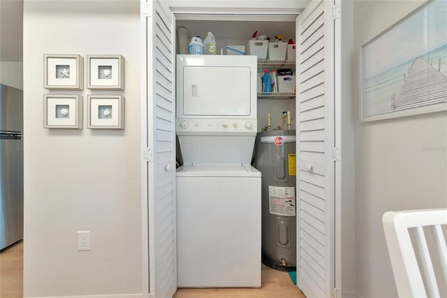 washroom featuring stacked washer / drying machine, water heater, and light wood-type flooring