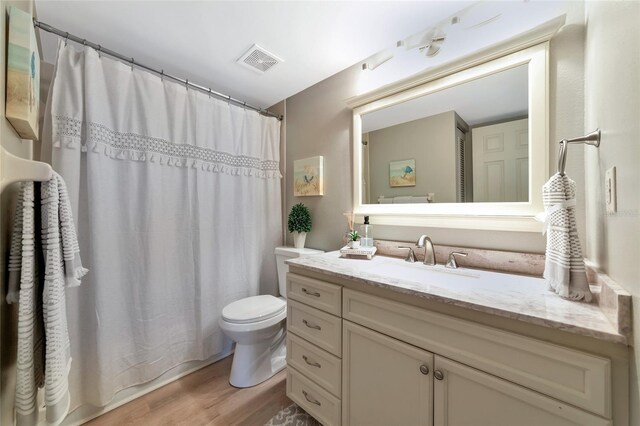bathroom featuring hardwood / wood-style flooring, vanity, toilet, and a shower with shower curtain