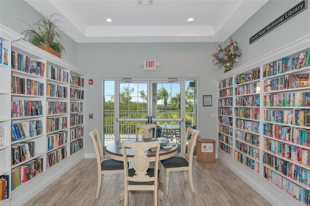 dining space featuring crown molding, a raised ceiling, and light wood-type flooring