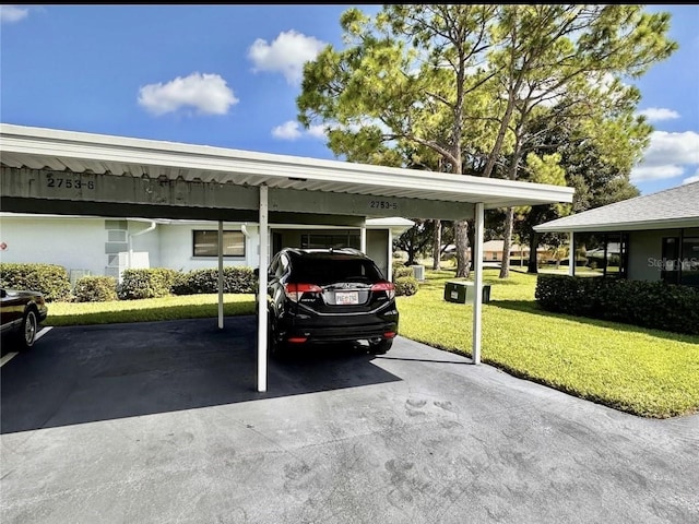 view of parking with a carport and a yard