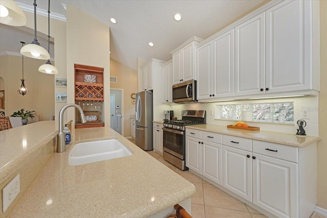 kitchen with white cabinetry, stainless steel appliances, a sink, and decorative light fixtures