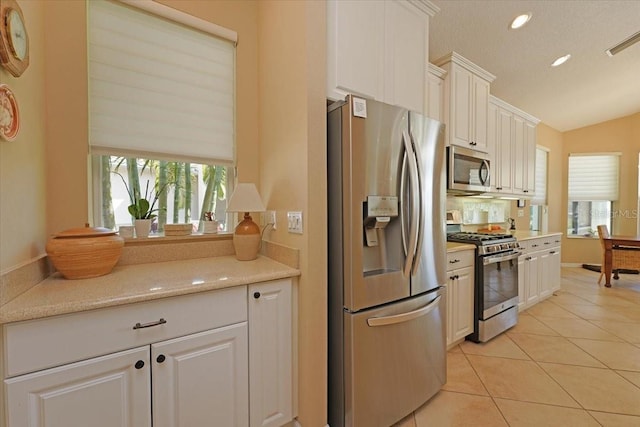 kitchen with appliances with stainless steel finishes, a wealth of natural light, visible vents, and light tile patterned floors