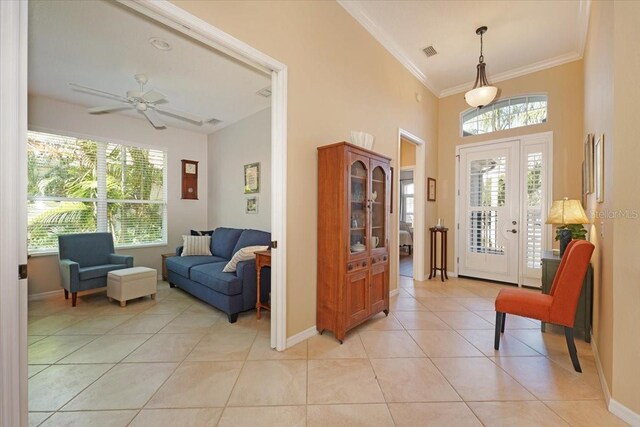 foyer entrance with crown molding, light tile patterned floors, visible vents, ceiling fan, and baseboards