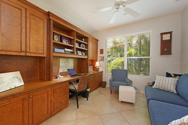 office area featuring a wealth of natural light, light tile patterned flooring, ceiling fan, and built in desk