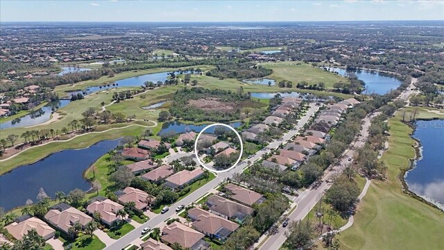 aerial view with golf course view, a water view, and a residential view