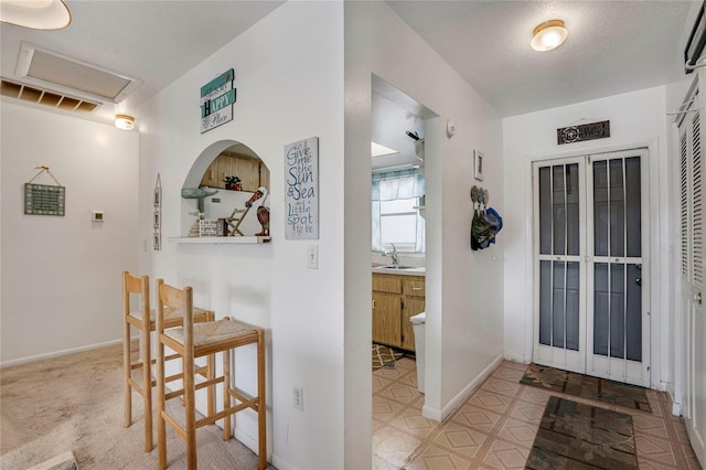 interior space with attic access, baseboards, tile patterned floors, a textured ceiling, and a sink