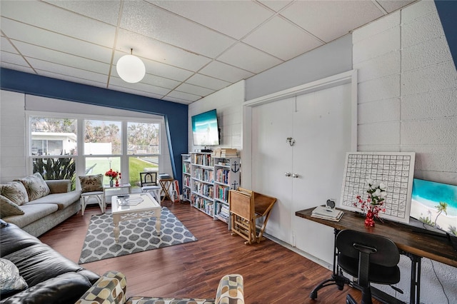 living room featuring dark wood finished floors and a drop ceiling