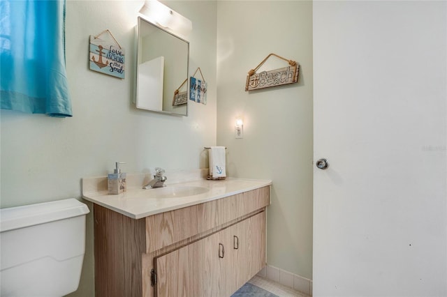 half bath with baseboards, vanity, and toilet