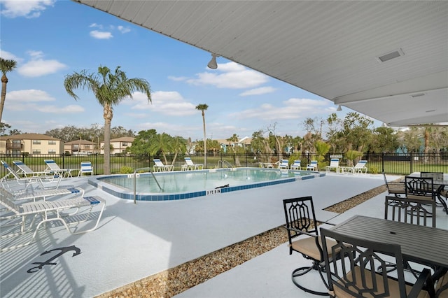 community pool with a patio and fence