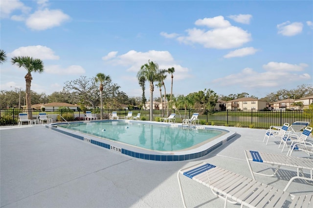 community pool with a patio area, a residential view, and fence