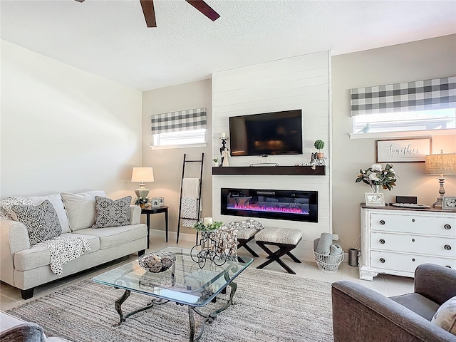 tiled living room with ceiling fan, plenty of natural light, and a textured ceiling