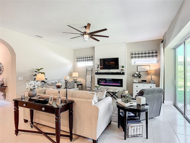 tiled living room featuring ceiling fan and a textured ceiling