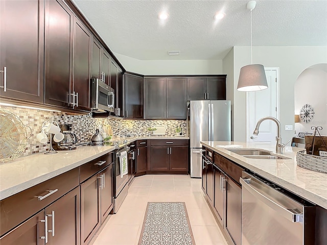 kitchen featuring hanging light fixtures, appliances with stainless steel finishes, sink, and dark brown cabinetry