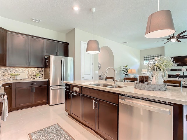 kitchen with appliances with stainless steel finishes, sink, pendant lighting, and dark brown cabinetry