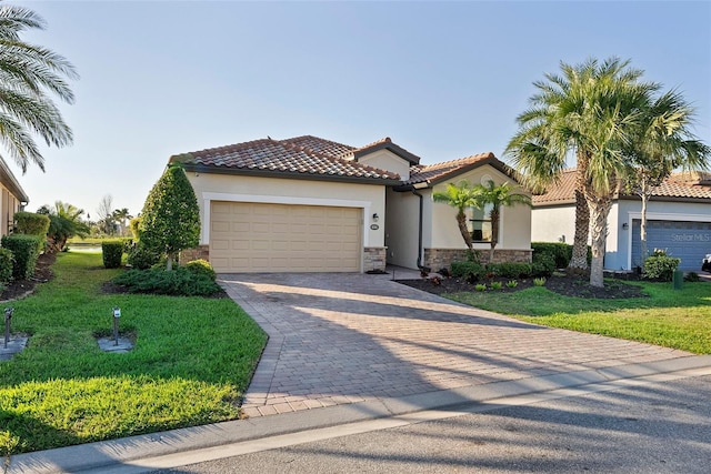 mediterranean / spanish house featuring decorative driveway, a front yard, an attached garage, and stucco siding