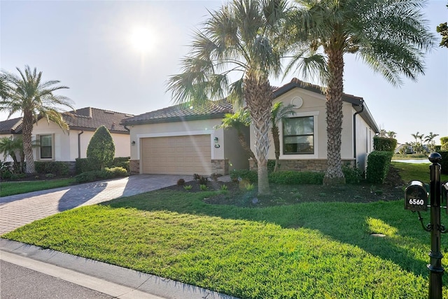 view of front of home featuring decorative driveway, stucco siding, an attached garage, stone siding, and a front lawn