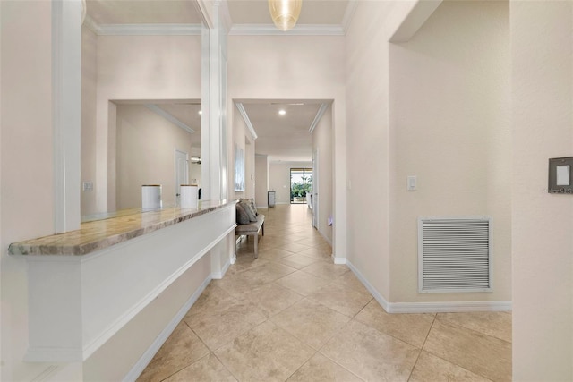 hallway with light tile patterned floors, baseboards, visible vents, and crown molding