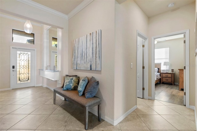 foyer with ornamental molding, light tile patterned flooring, and baseboards