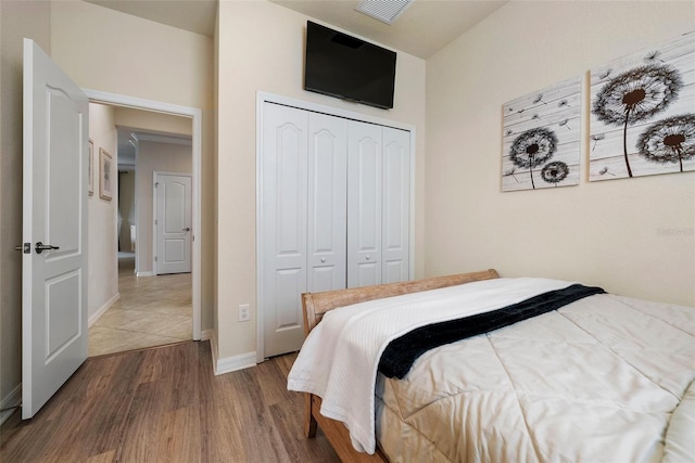 bedroom featuring a closet, wood finished floors, visible vents, and baseboards