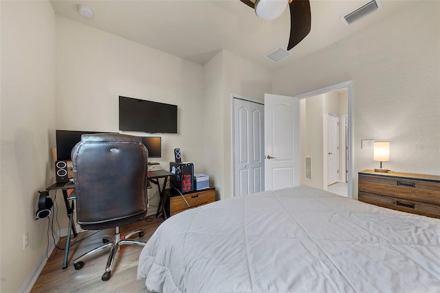 bedroom with a closet, visible vents, baseboards, and wood finished floors