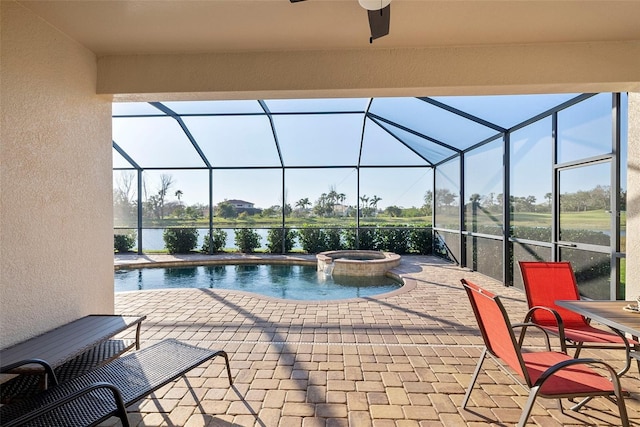 view of pool featuring glass enclosure, a patio area, a pool with connected hot tub, and a water view