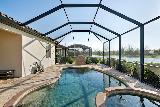 view of pool with a patio area, a pool with connected hot tub, a water view, and glass enclosure