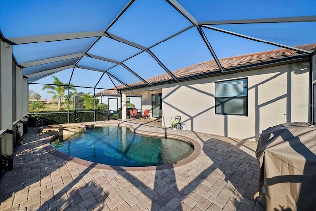 view of pool featuring a pool with connected hot tub, a patio area, grilling area, and a lanai