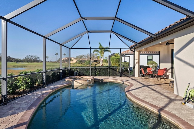 view of swimming pool featuring a pool with connected hot tub, glass enclosure, ceiling fan, and a patio