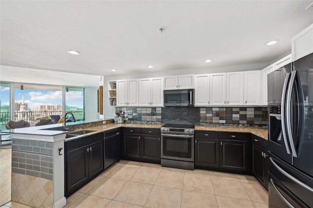 kitchen featuring decorative backsplash, stainless steel appliances, dark cabinetry, white cabinetry, and a sink